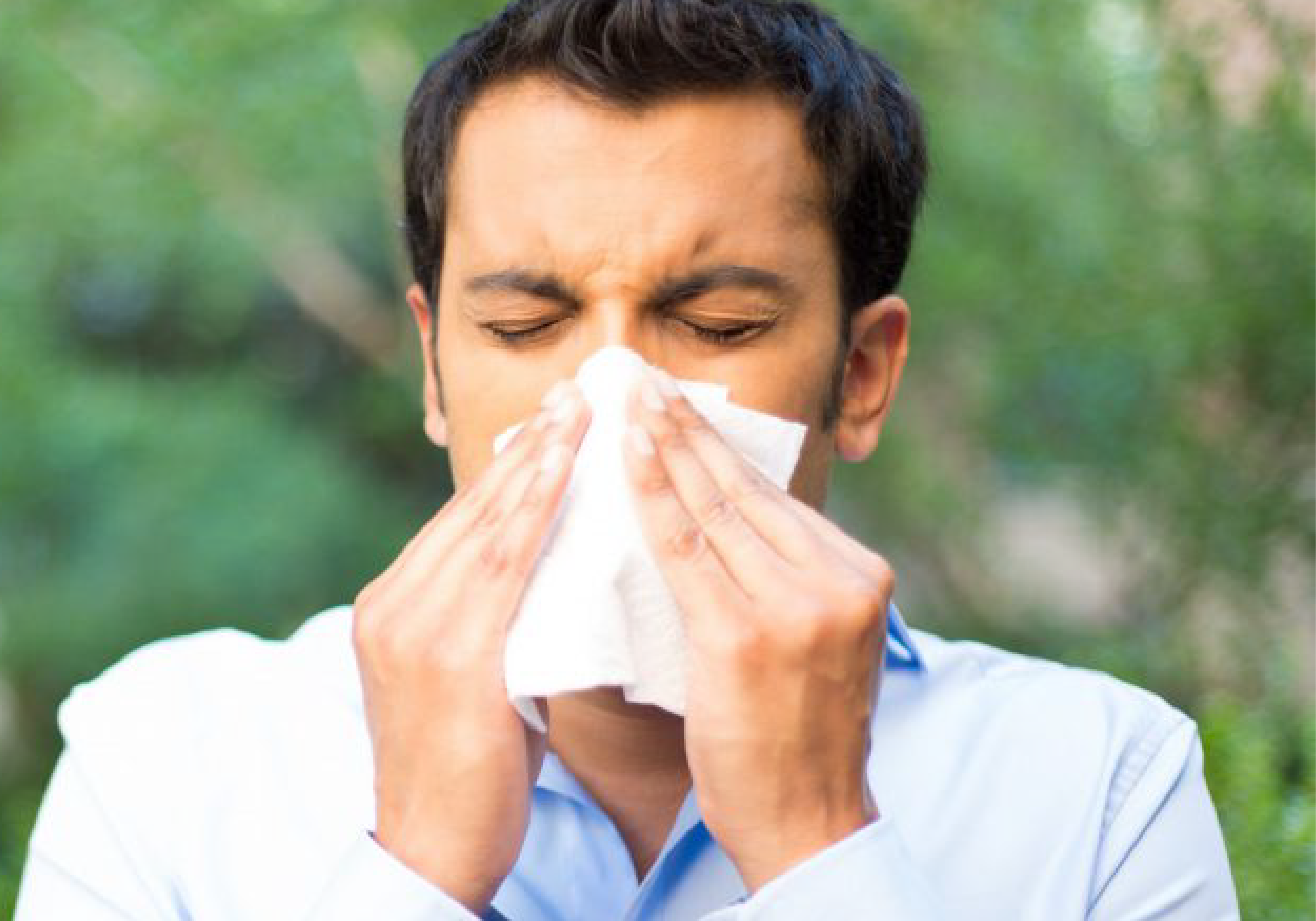 Allergy Clinic Box: Person sneezing into a tissue outdoors, illustrating allergy symptoms and seasonal health concerns.