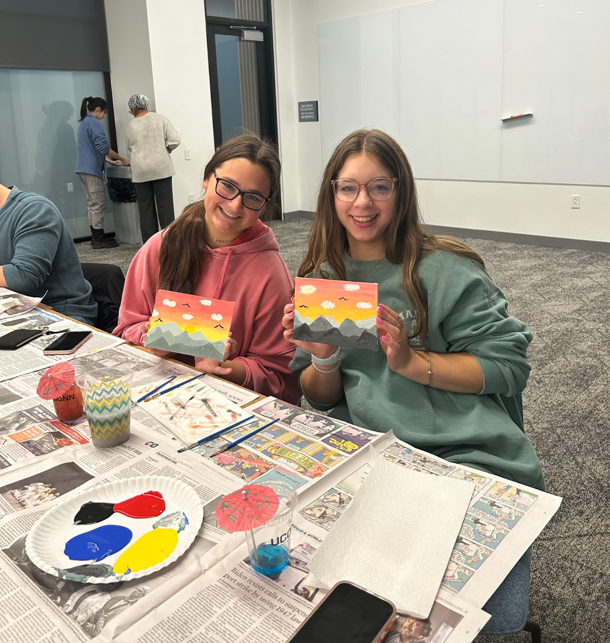 Holistic Huskies painting2 Students smile while showing their completed mountain sunset paintings during a Student Health and Wellness art event.