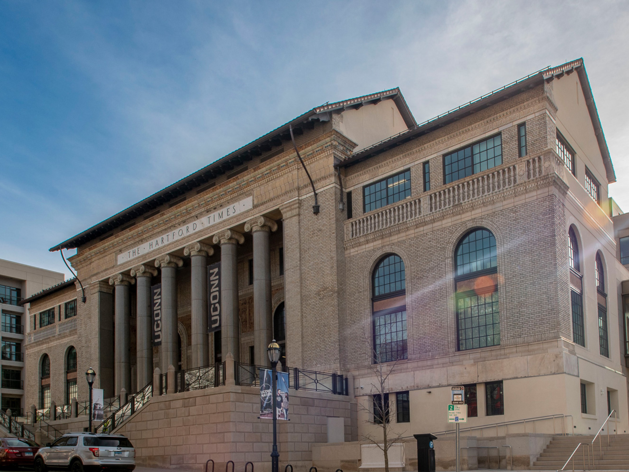 Exterior view of UConn Hartford’s historic building with tall columns and UConn banners displayed at the entrance