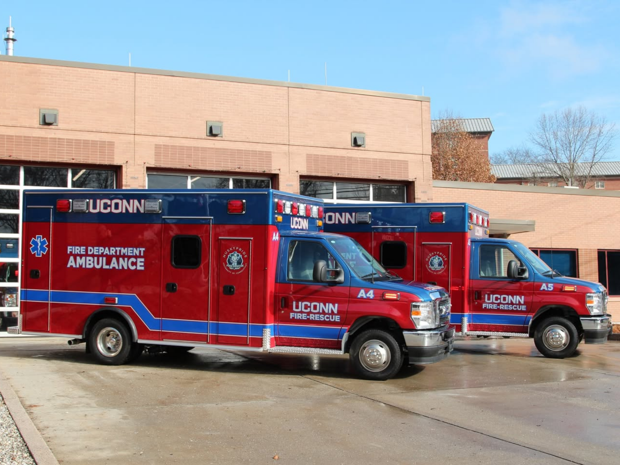 Two UConn Fire Department ambulances are parked outside a campus building.
