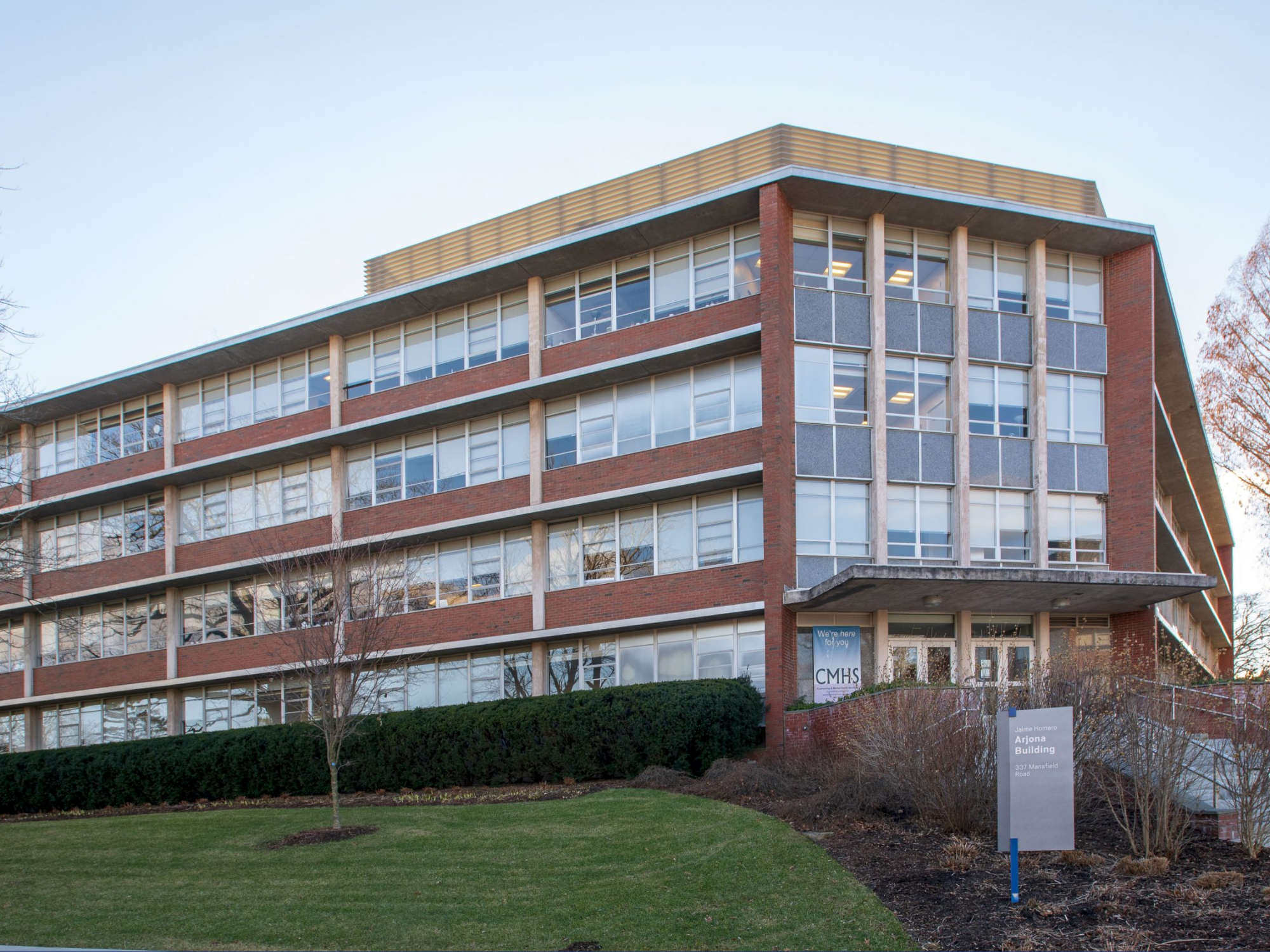 Exterior view of the Arjona Building with large windows and landscaped lawn in front.