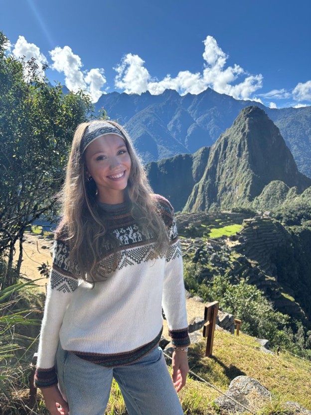 Student smiles at a scenic mountain overlook during a sunny outdoor visit.