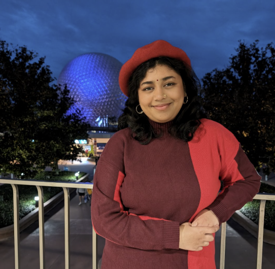 Student smiles while standing on a balcony at a campus-themed location during an evening outing.