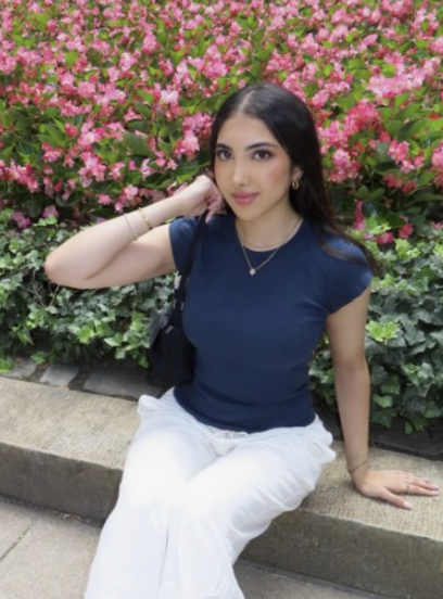 Student poses in front of blooming flowers on campus.