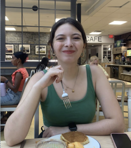 Student sits at a table in a campus café enjoying a meal.